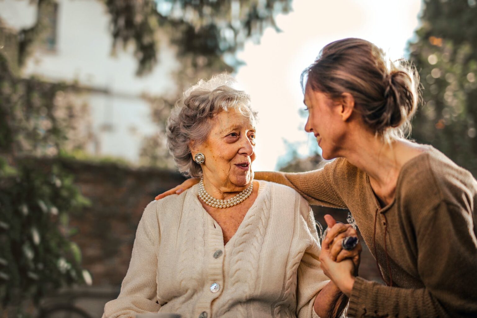 Pourquoi votre tante est votre meilleure amie ? Joyful adult daughter greeting happy surprised senior mother in garden