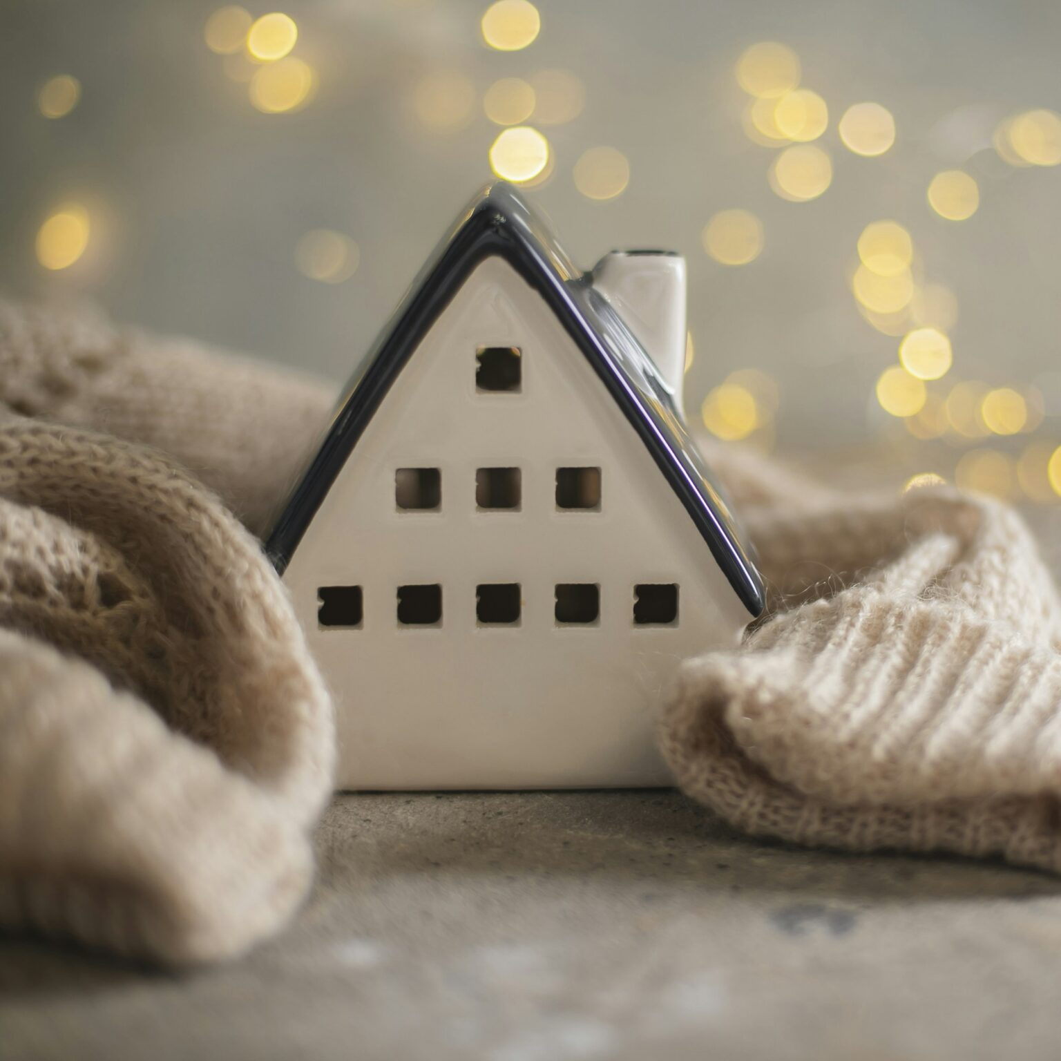 Ceramic house insulated by warm sweater. Concept of protection of house and lack of heat at home