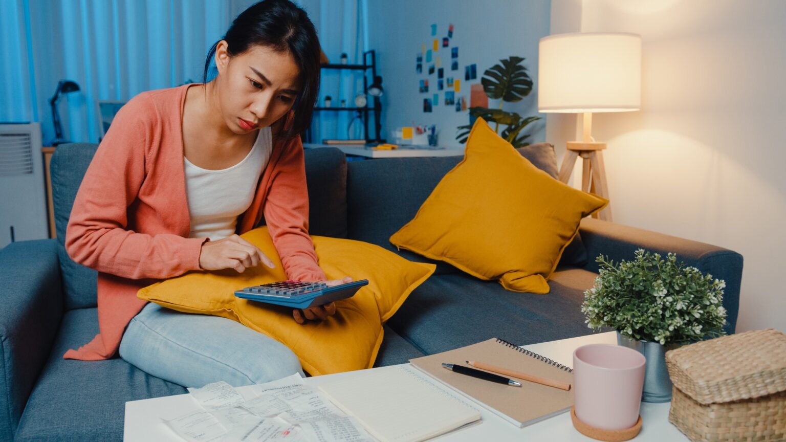 Impossible de payer les travaux de la copropriété : solutions et conséquences Asian lady feel stress and worried with bill and invoice credit card calculating loan on sofa.