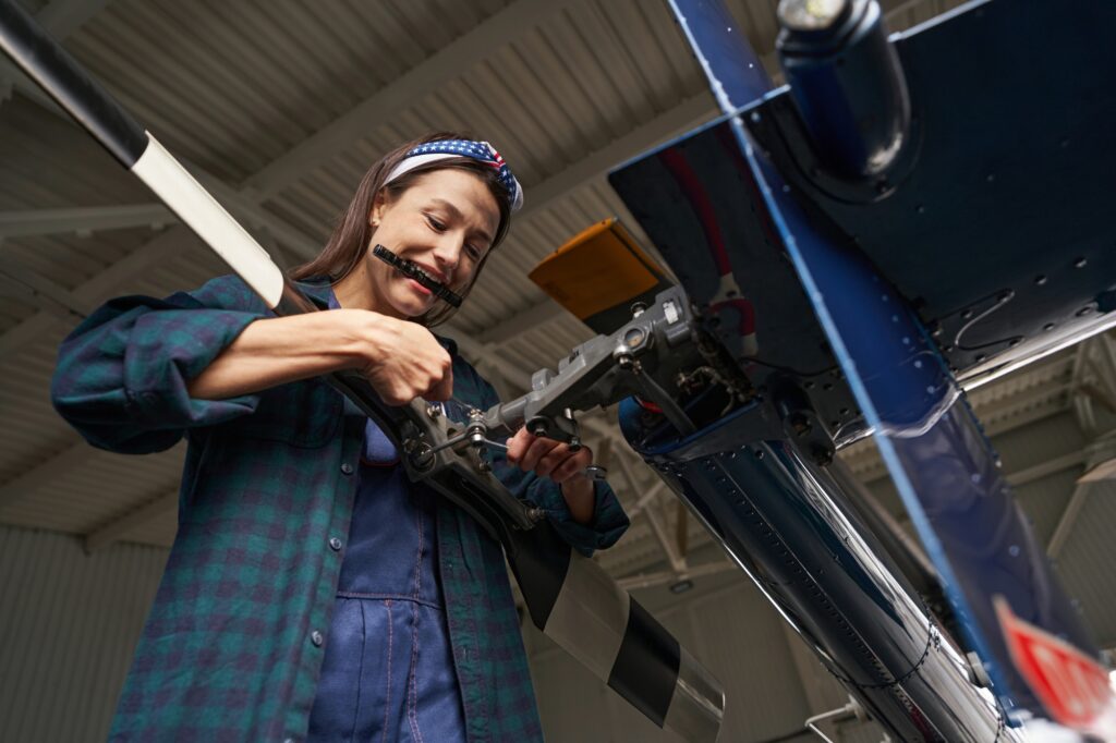 Female engineer modernization and renovating motor of airplane in hangar