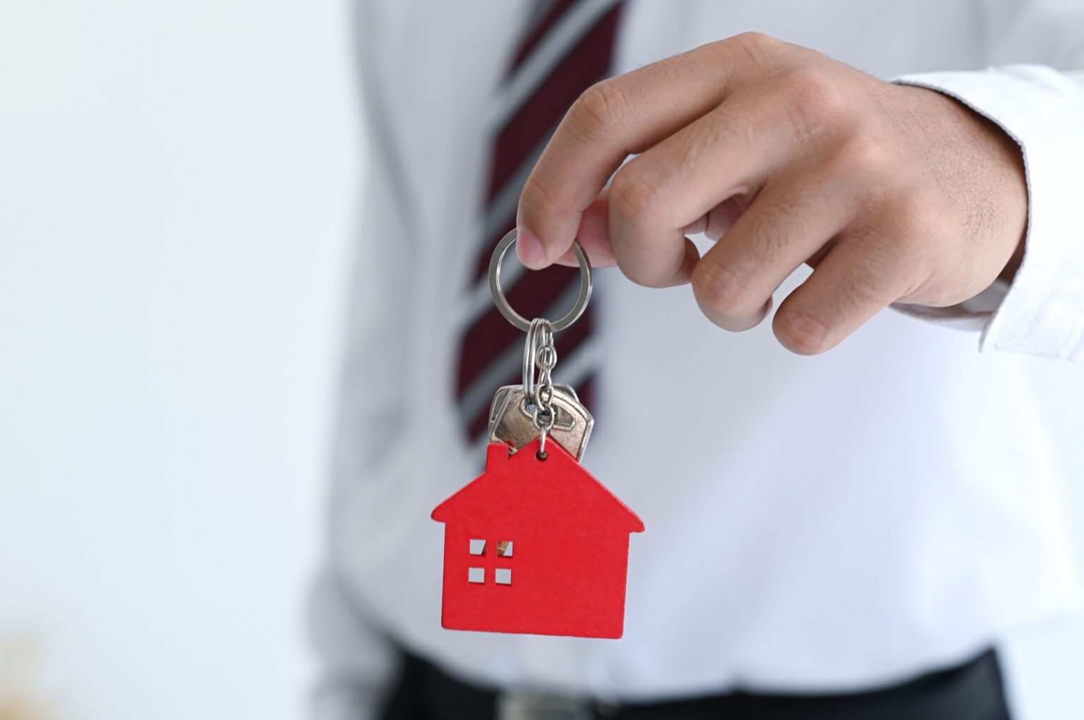 Square Habitat : votre partenaire immobilier de confiance Male hand holding a keychain with model house, real estate trading concept, real estate insurance.