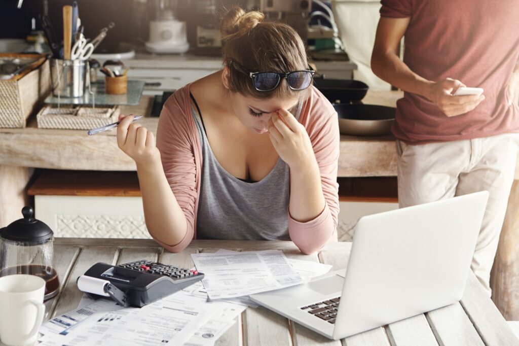 Young family facing debt problems, can't pay out their mortgage. Stressed woman holding her head in