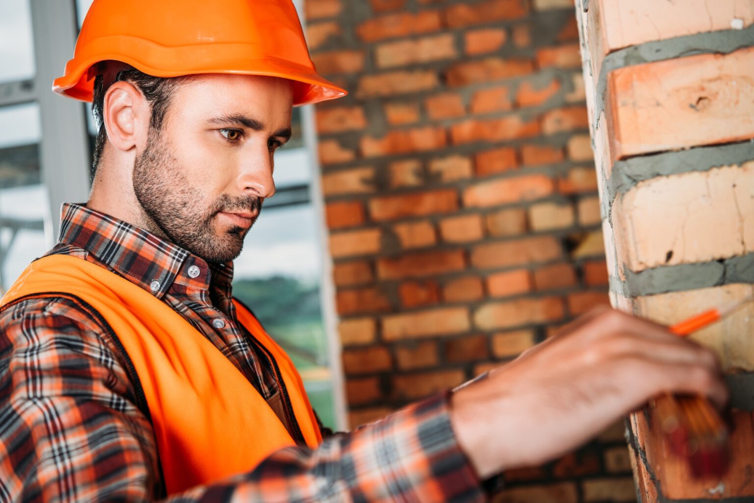 handsome young builder doing measurements at construction site