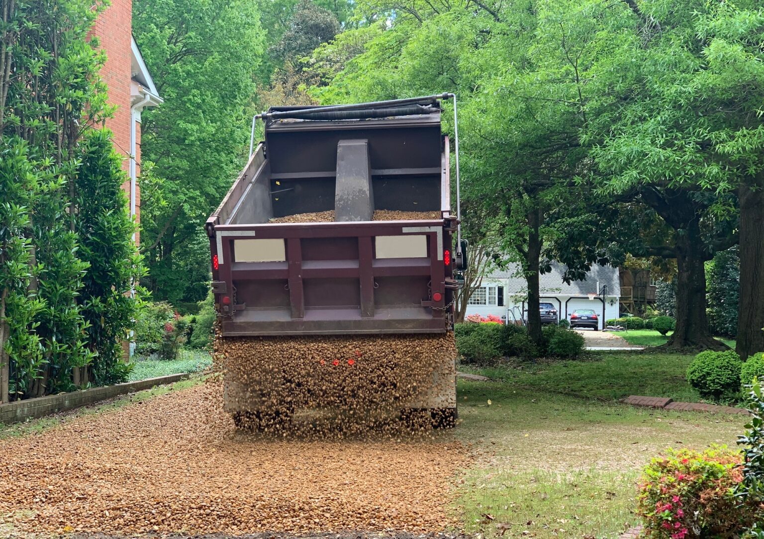 Truck putting new gravel on home’s driveway which needed improvement since gravel was already low