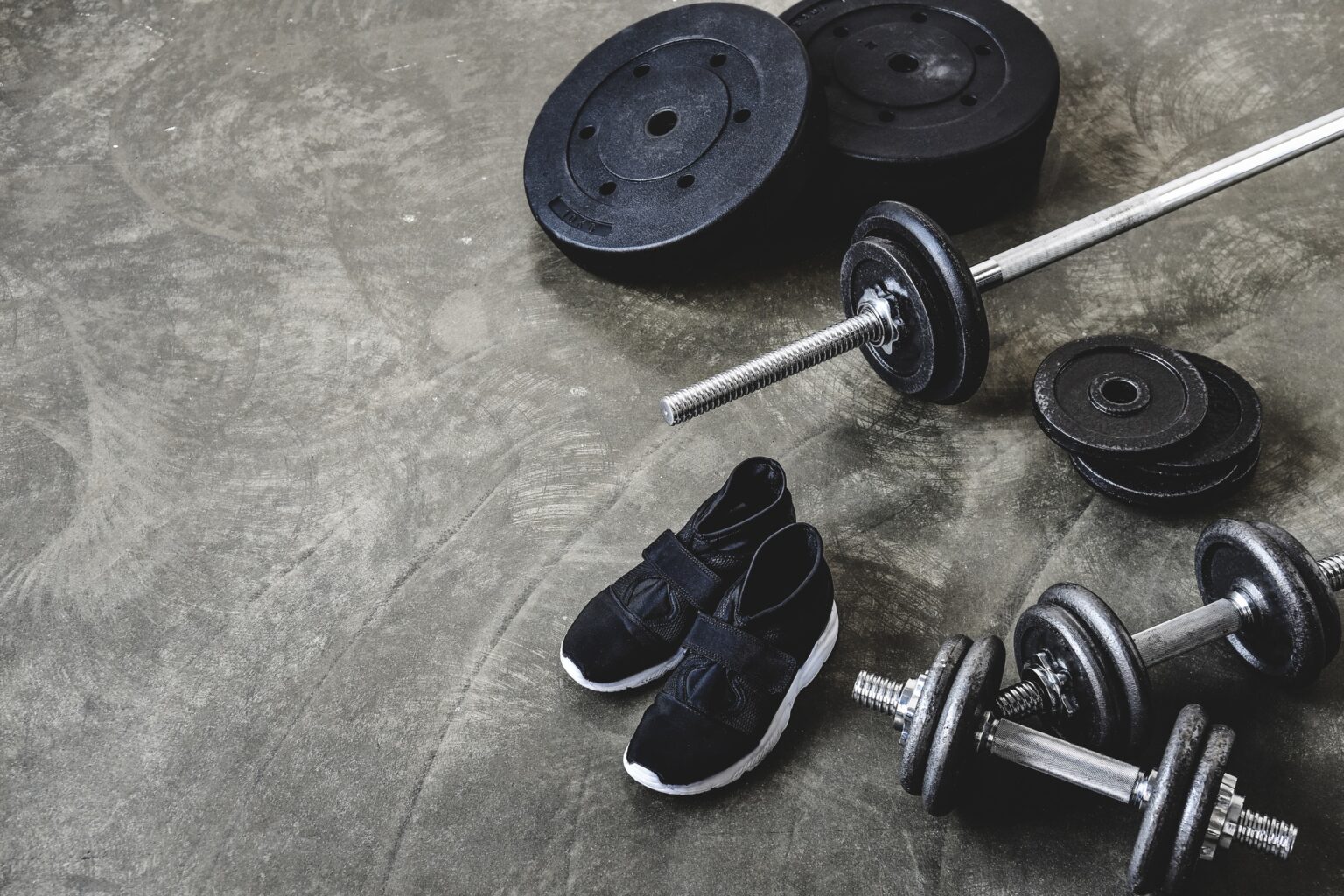Comment déterminer le poids d’un mètre cube de béton en kilogrammes dumbbells and barbell with weight plates and sneakers on concrete floor