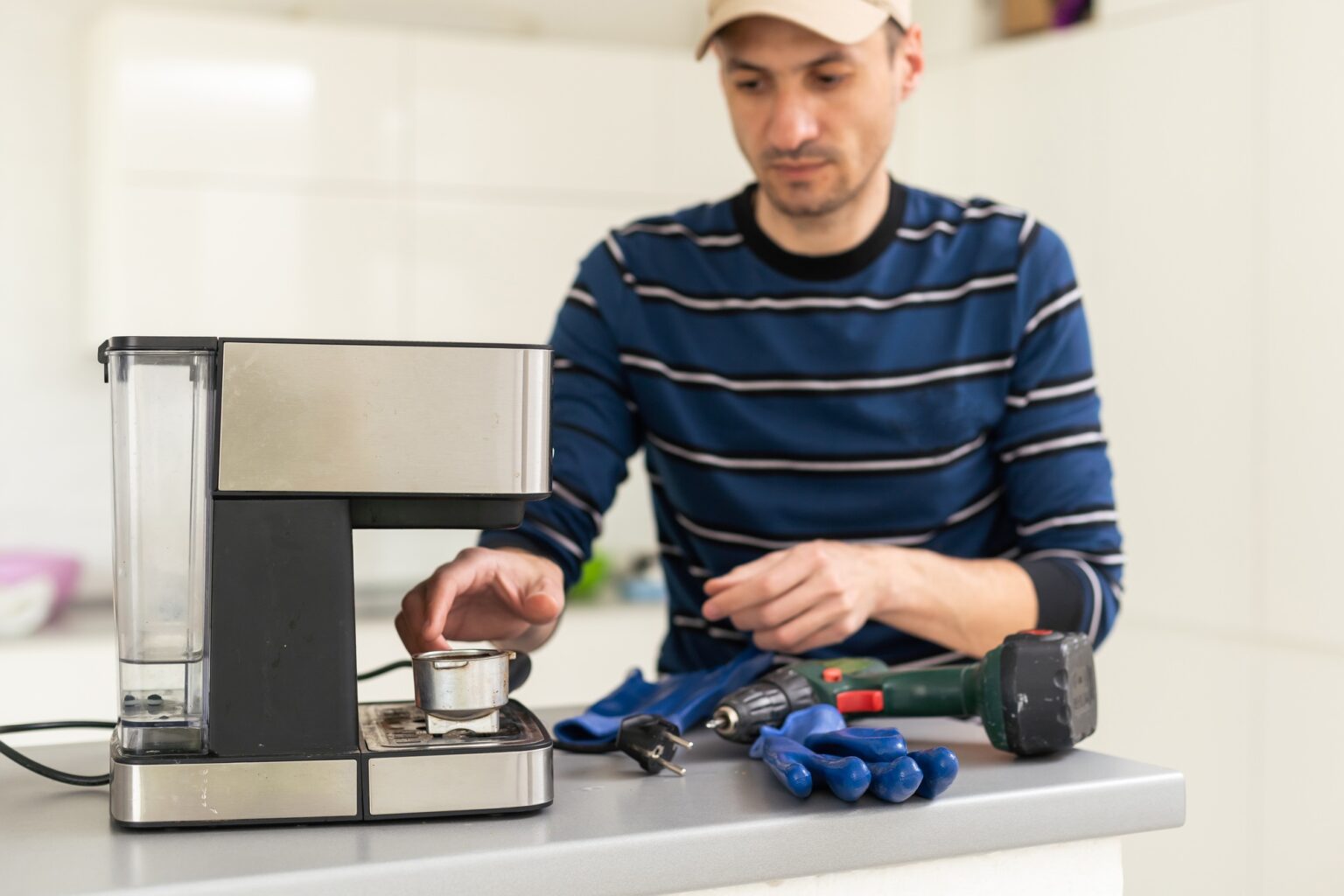 Detartrage de cafetière : un geste simple pour savourer chaque tasse Professional young repairman repairs a coffee maker. Handsome worker in uniform repairing coffee